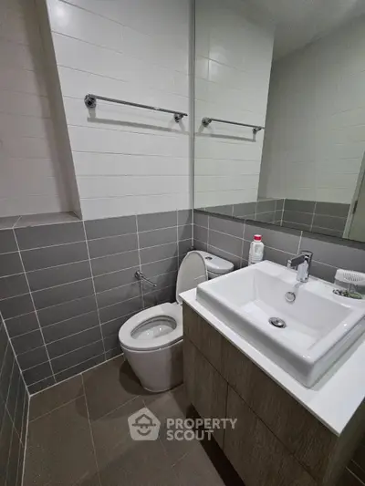 Modern bathroom with sleek design, featuring a stylish sink and toilet in a compact space.