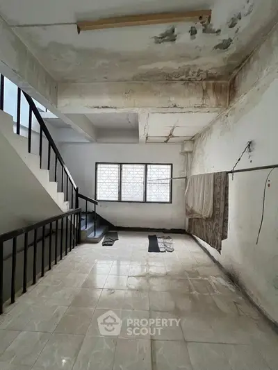 Spacious interior with staircase and large windows, ideal for renovation projects.