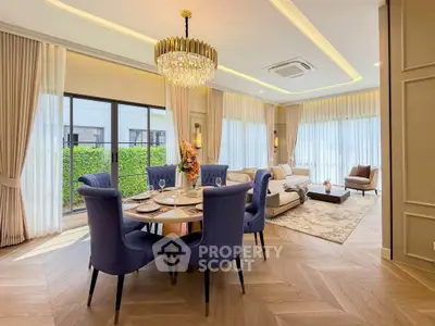Luxurious living room with elegant dining area, featuring a stunning chandelier and large windows for natural light.