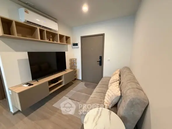 Modern living room with sleek furniture and large TV in cozy apartment.