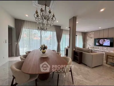 Luxurious open-plan living and dining area with elegant chandelier and modern decor.