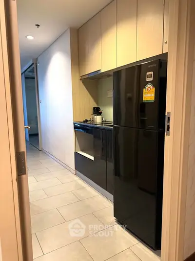 Modern kitchen with sleek black fridge and minimalist design in a stylish apartment.