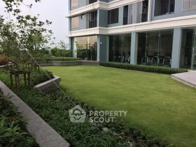 Modern building exterior with lush green garden and glass facade