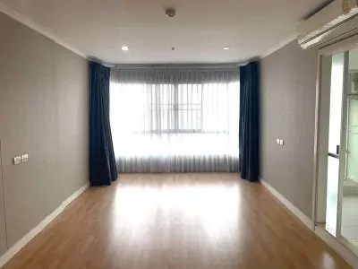 Spacious empty living room with large window and wooden flooring, ready for customization.