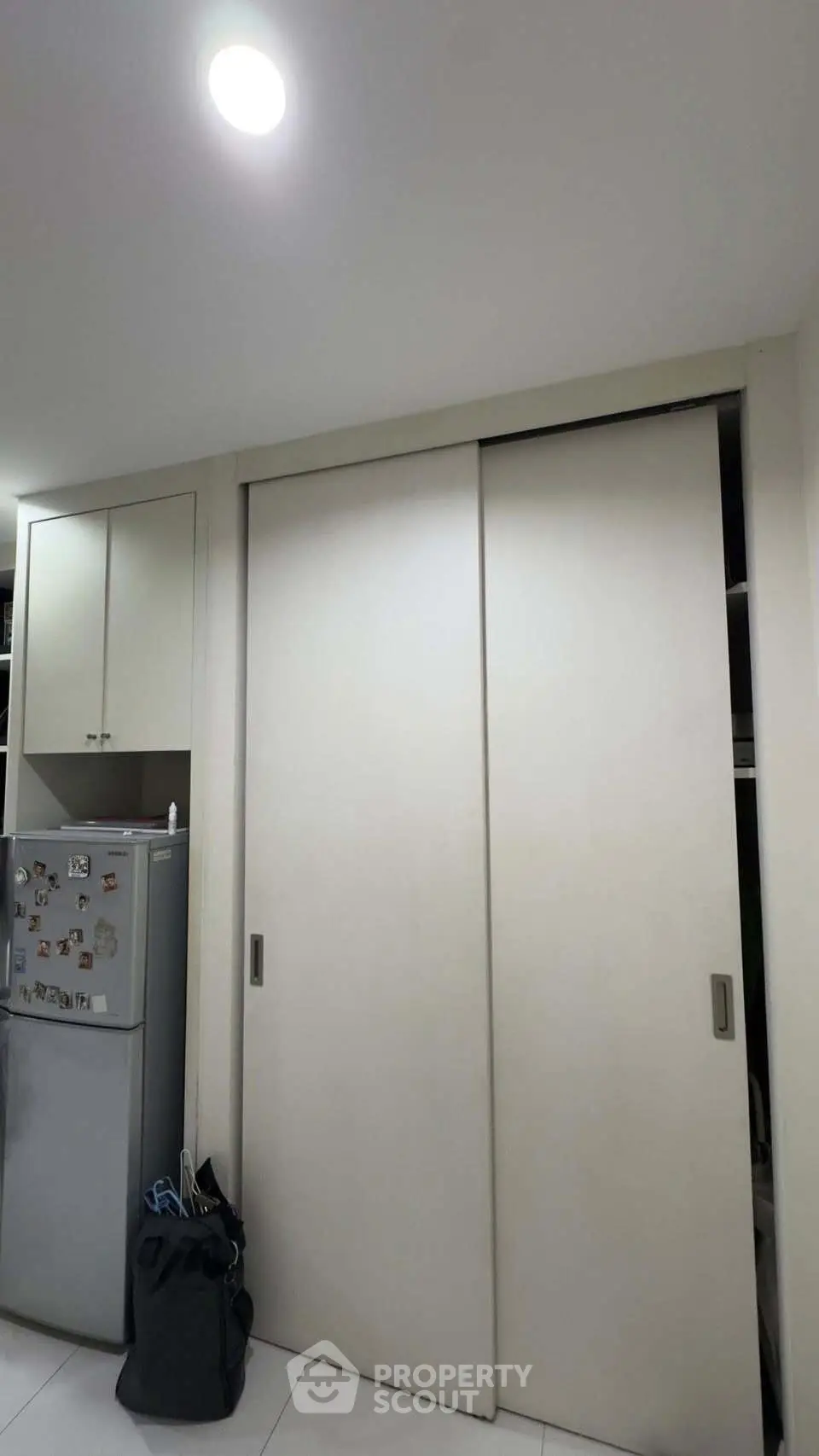 Modern kitchen with sleek cabinets and stainless steel fridge in compact layout.
