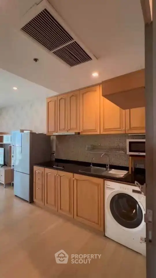 Spacious kitchen with wooden cabinets and modern appliances in a cozy apartment.