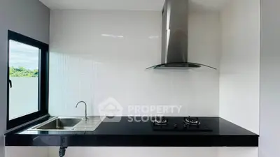 Modern kitchen with sleek black countertop and gas stove, featuring a large window for natural light.