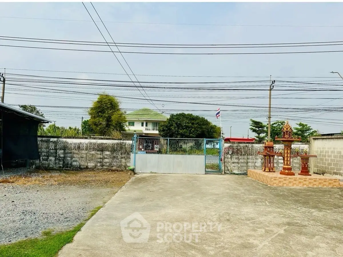 Spacious property with gated entrance and traditional spirit house in serene setting.