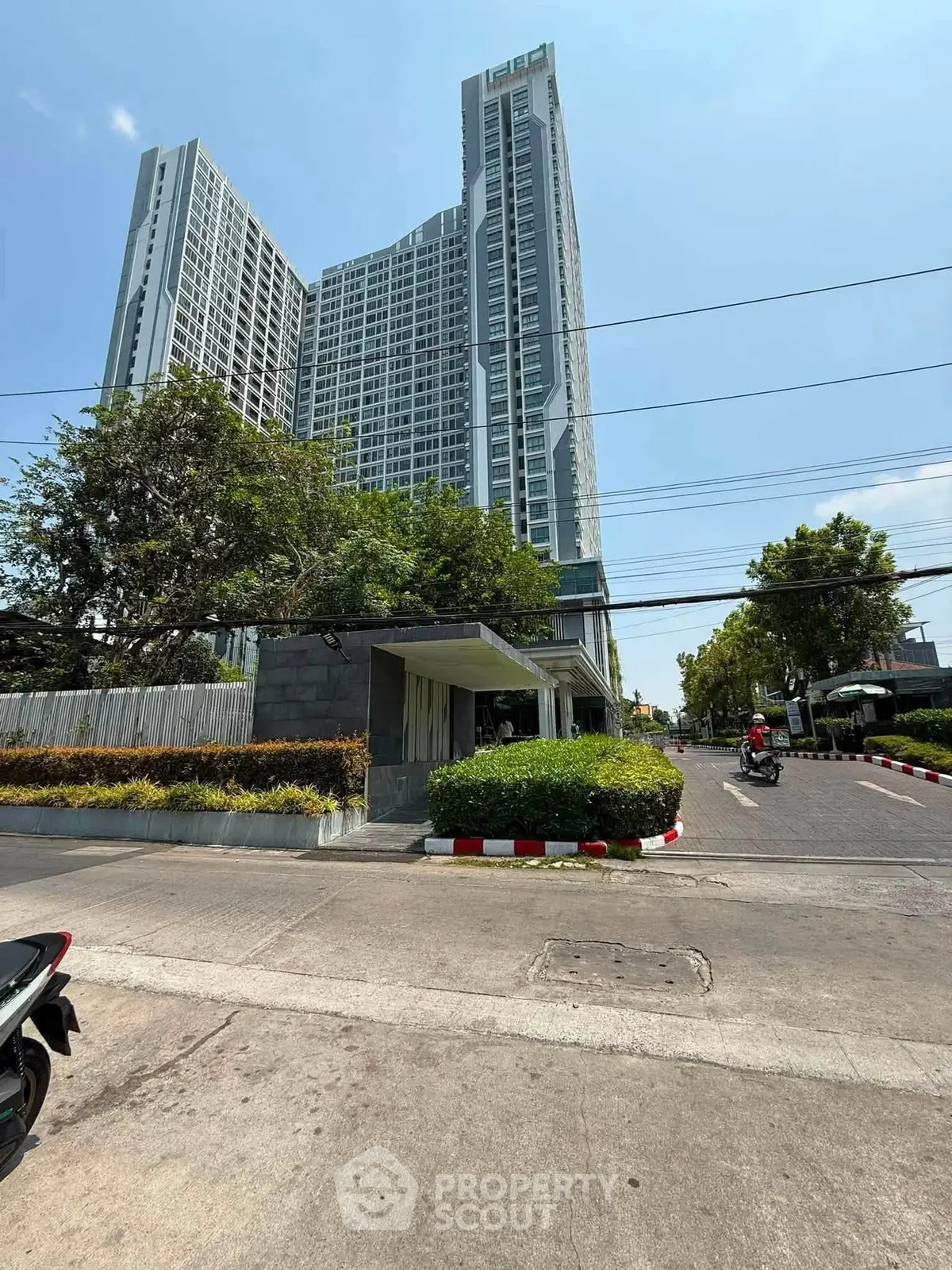 Modern high-rise condominium with lush landscaping and clear blue sky