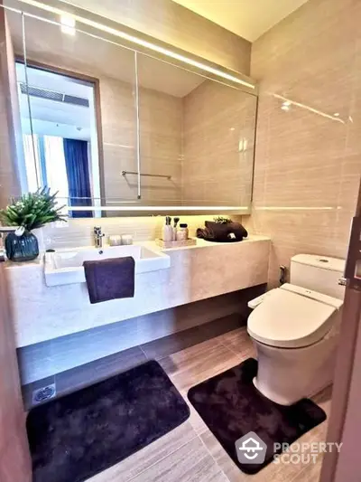 Modern bathroom with sleek design, featuring a large mirror, undermount sink, and a well-lit ambiance perfect for relaxation and self-care routines.