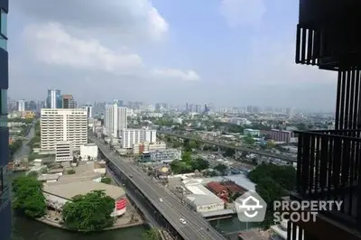 Expansive cityscape view from a high-rise balcony showcasing urban living at its finest, with clear skies and bustling streets below.