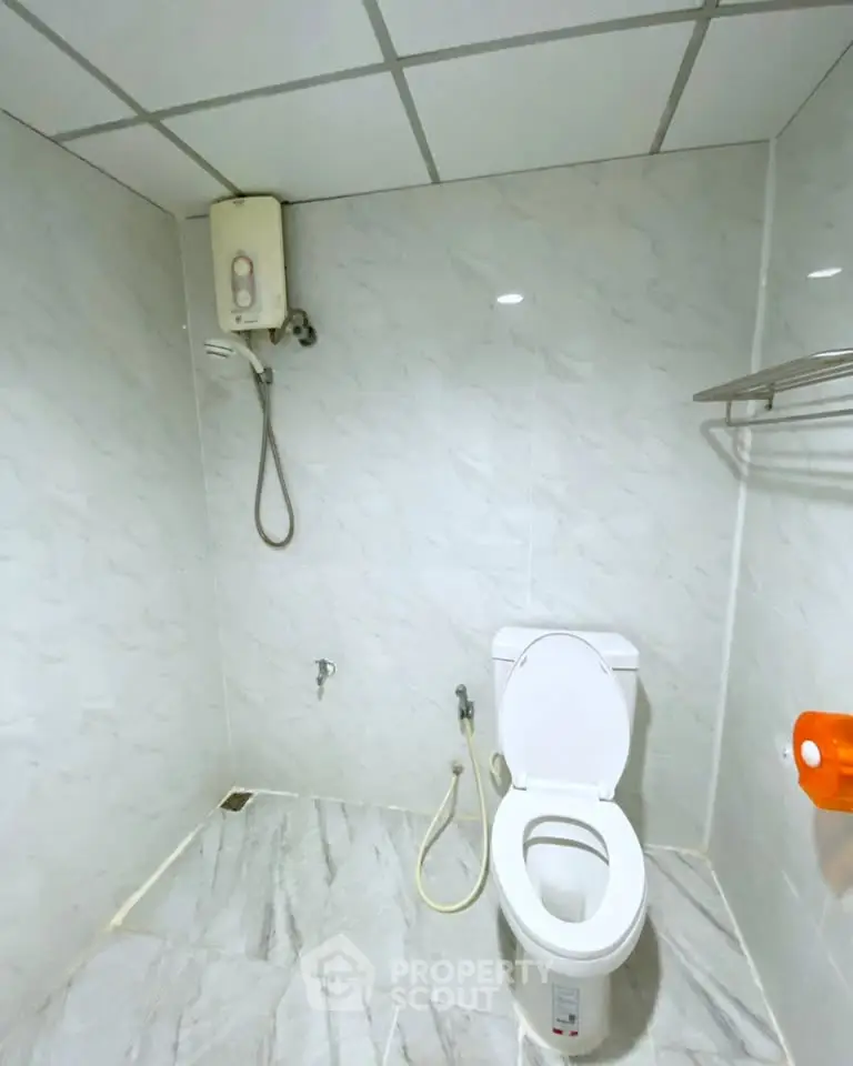 Modern bathroom with sleek white tiles and essential fixtures, offering a clean and minimalist design.
