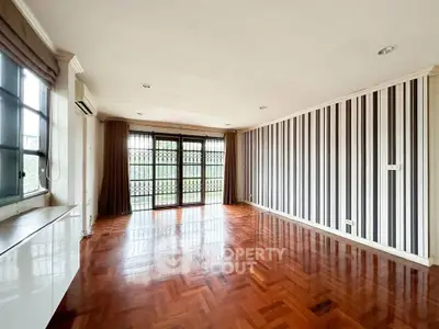Spacious living room with elegant wooden flooring and large windows for natural light.