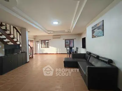 Spacious living room with modern decor and staircase, perfect for family gatherings.