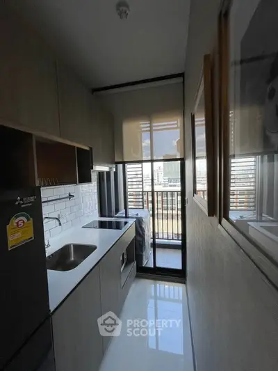 Modern kitchen with sleek cabinetry and balcony view in urban apartment