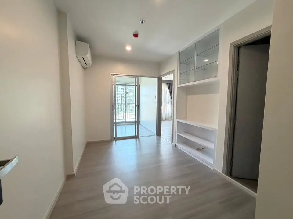 Modern living room with built-in shelves and balcony access in a bright apartment.