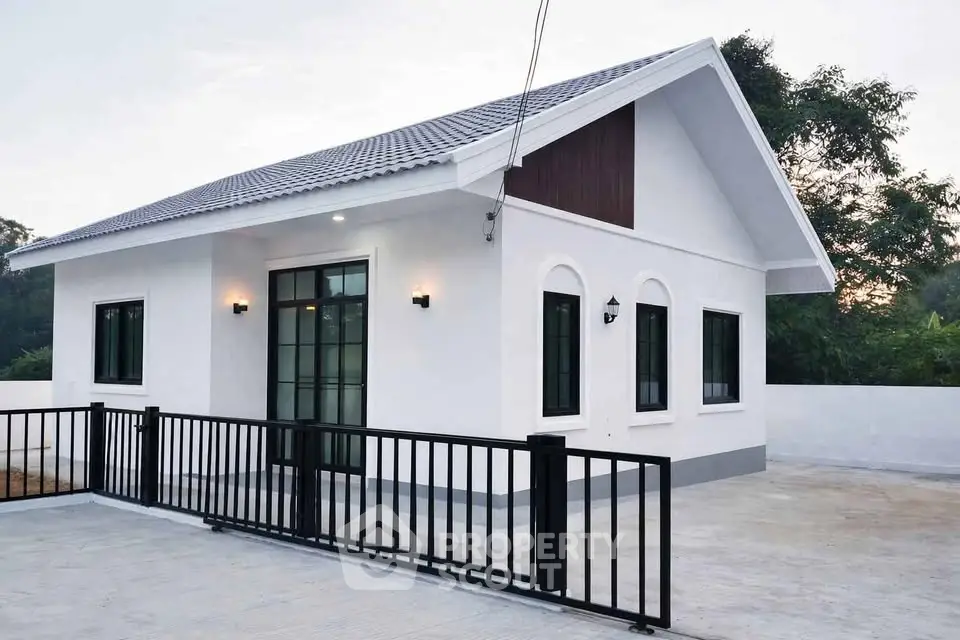 Charming modern single-story house with sleek black fence and spacious driveway, ideal for serene living.