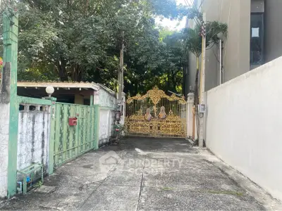Charming gated entrance with ornate golden gate and lush greenery, perfect for privacy and elegance.