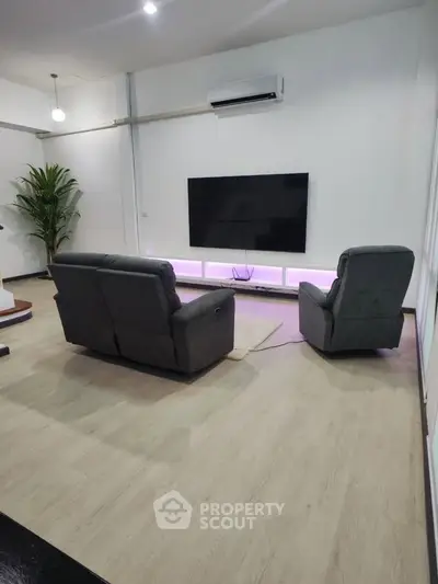 Modern living room with sleek furniture and large TV, perfect for entertainment and relaxation.