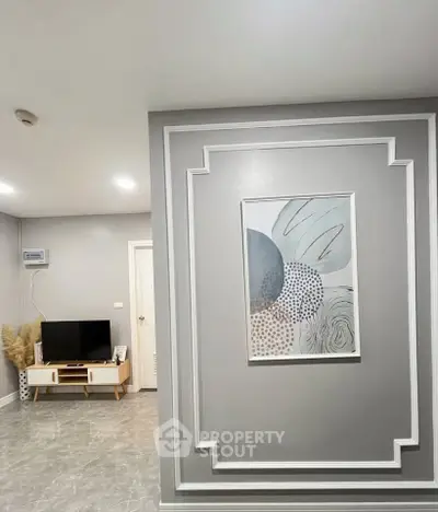 Modern living room with stylish decor and wall art, featuring a sleek TV stand and elegant grey tones.