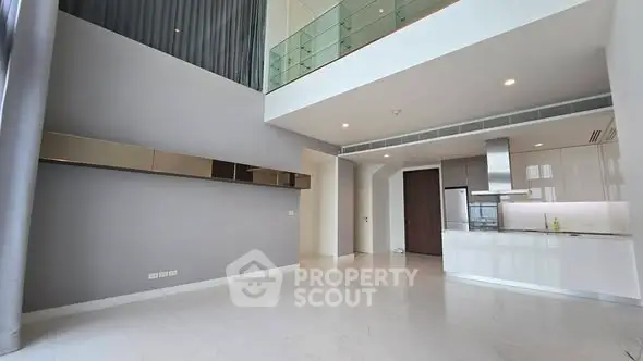 Spacious modern living room with high ceilings and open kitchen layout in luxury apartment.