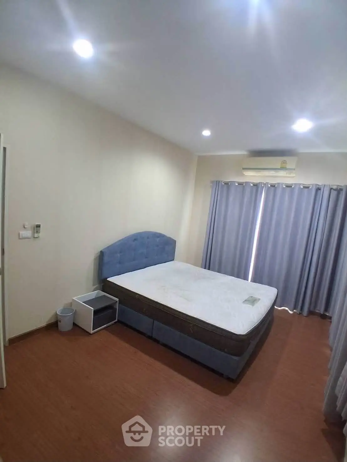 Spacious bedroom with modern furnishings and natural light, featuring a comfortable bed and elegant curtains.