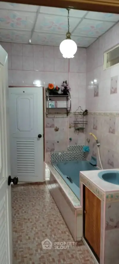 Charming vintage bathroom with unique blue bathtub and floral tiles.