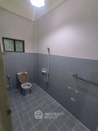 Modern bathroom with tiled walls and floor, featuring a shower and toilet.