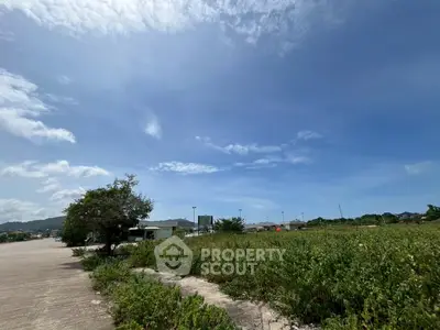 Expansive land with lush greenery under a clear blue sky, ideal for development opportunities.