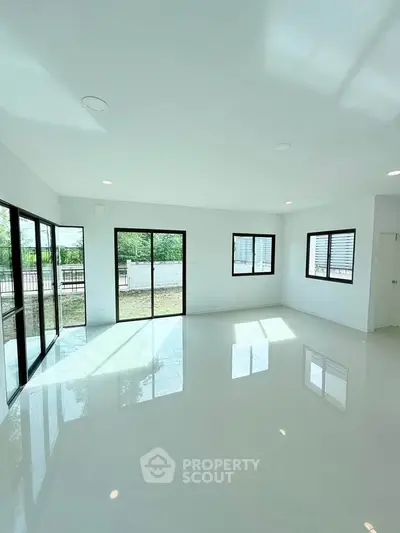 Spacious sunlit living room with large windows and glossy floors, offering a bright and airy ambiance.