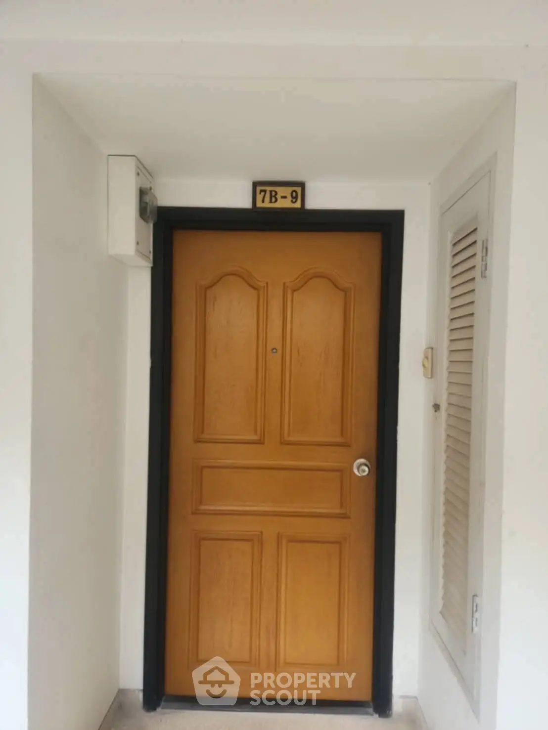 Stylish wooden apartment door with unit number 7B-9 in modern building.