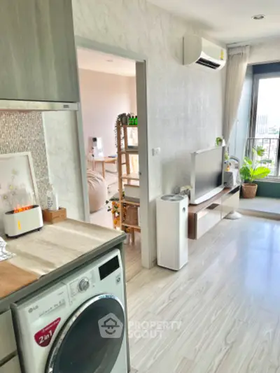 Modern apartment interior with open layout, featuring kitchen and living room with balcony view.