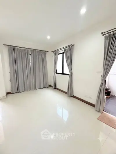 Spacious unfurnished room with large windows and elegant curtains, perfect for customization.