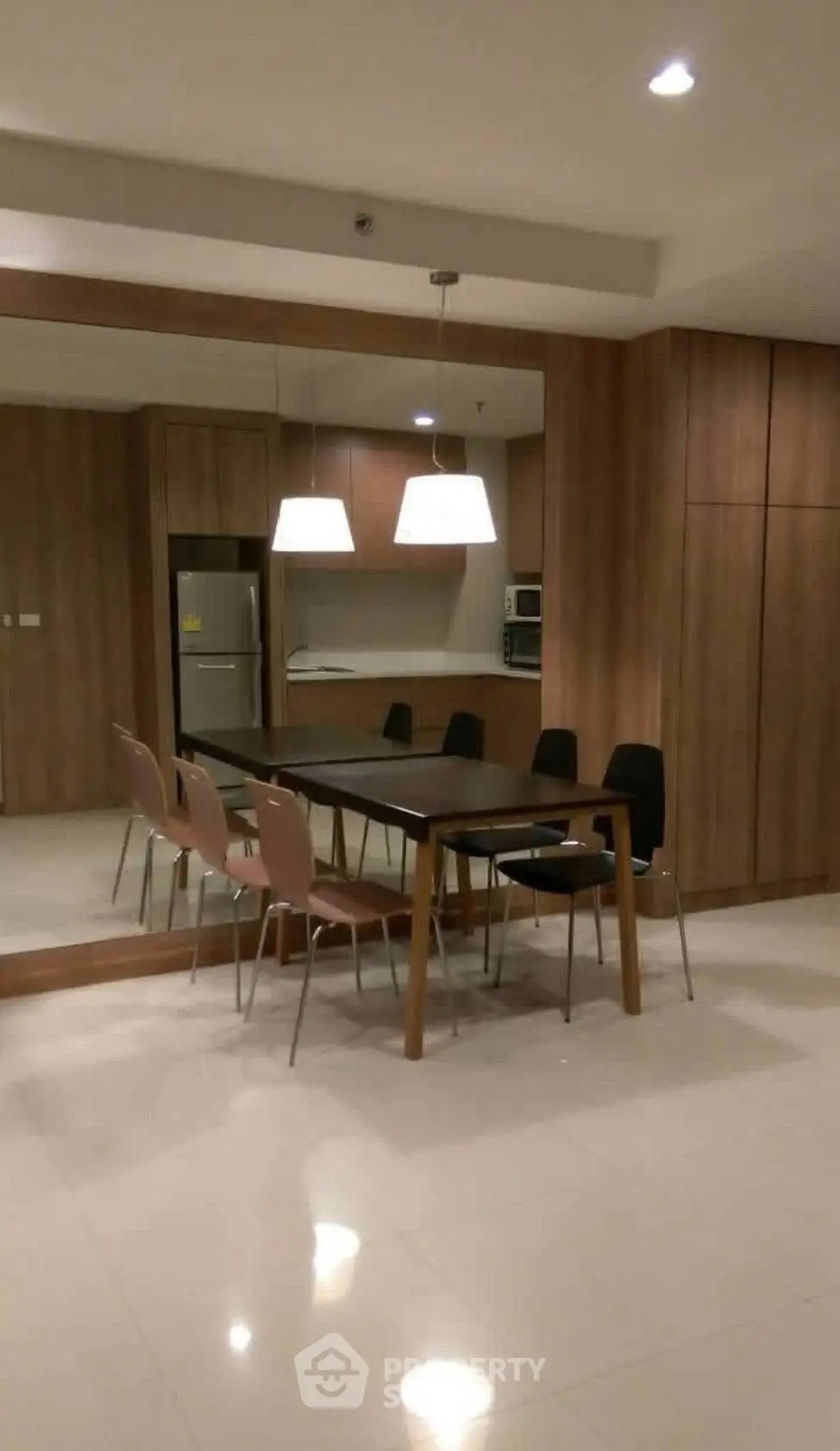Modern dining area with sleek wooden furniture and contemporary lighting in a stylish apartment.