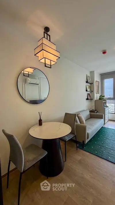 Modern living room with stylish furniture and large window offering natural light and city view.