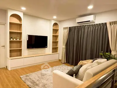 Modern living room with cozy sofa, wall-mounted TV, and elegant shelving.