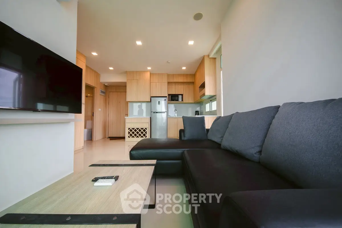 Modern living room with sleek black sofa and open kitchen layout