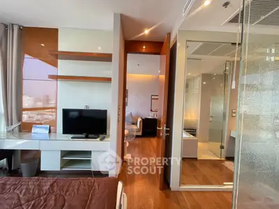 Modern bedroom with glass-walled bathroom and sleek wooden flooring