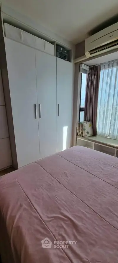 Cozy bedroom with natural light, featuring a built-in wardrobe and air conditioning.