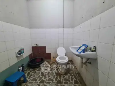 Simple bathroom with tiled walls and floor, featuring a toilet and sink.