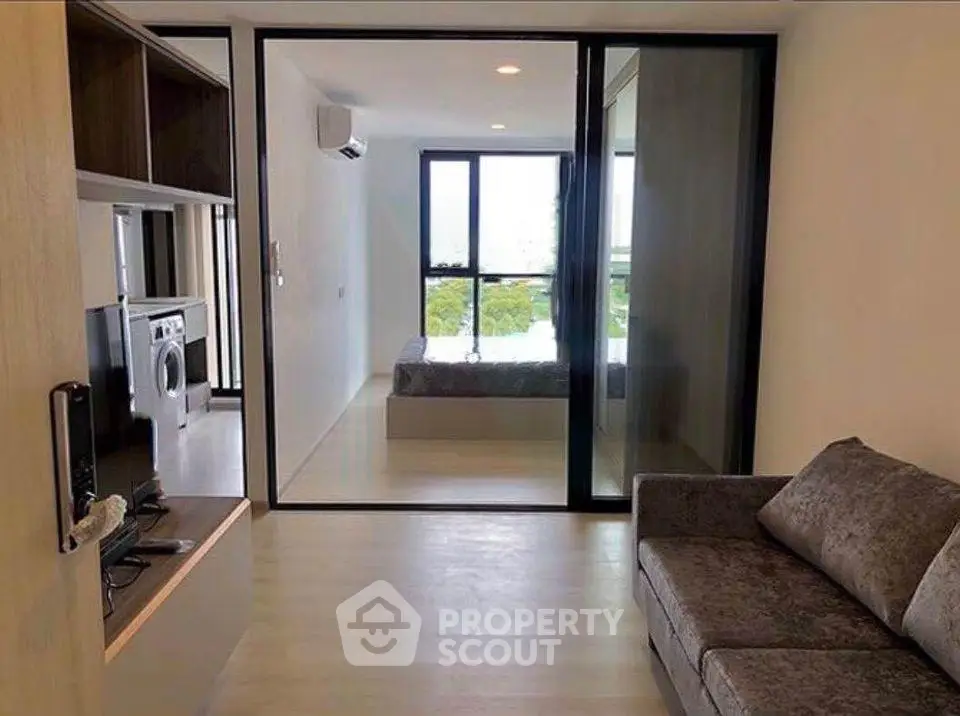 Modern apartment interior with cozy living room and bedroom view, featuring sleek furniture and large windows.