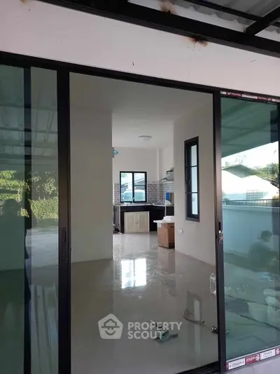 Modern interior with sliding glass doors and tiled flooring, leading to a compact kitchen area.