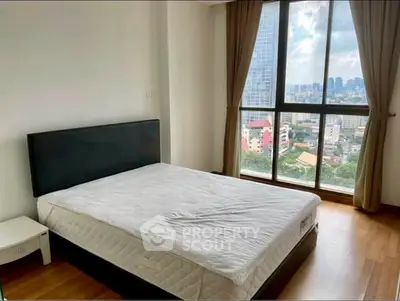 Spacious bedroom with large window offering stunning city view in modern apartment.