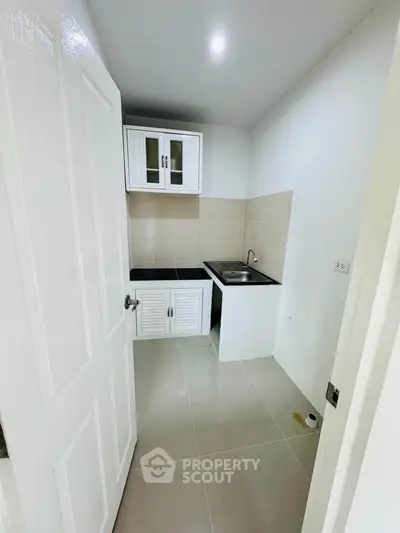 Compact kitchen with white cabinets and tiled backsplash in modern apartment