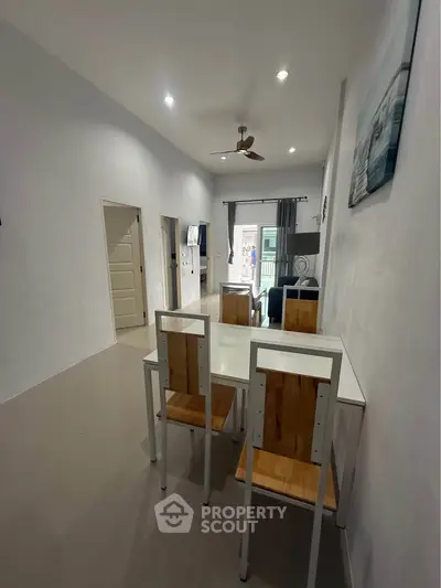 Modern dining area with wooden chairs and sleek table in a bright, open-plan living space.