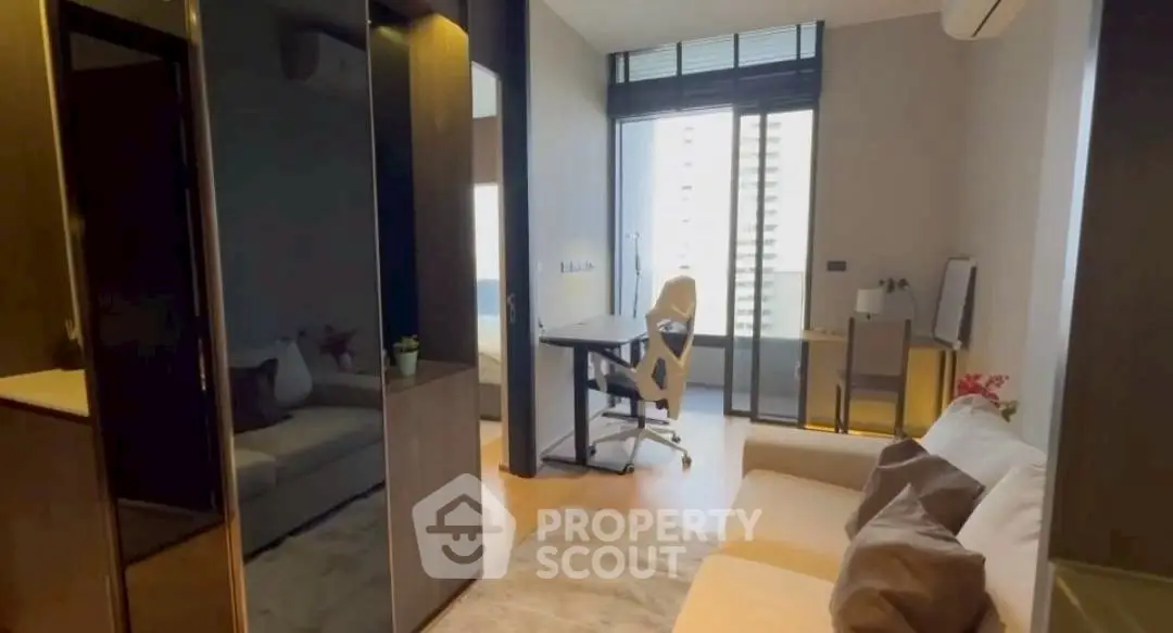Modern living room with stylish furniture and workspace, featuring large windows and sleek design.