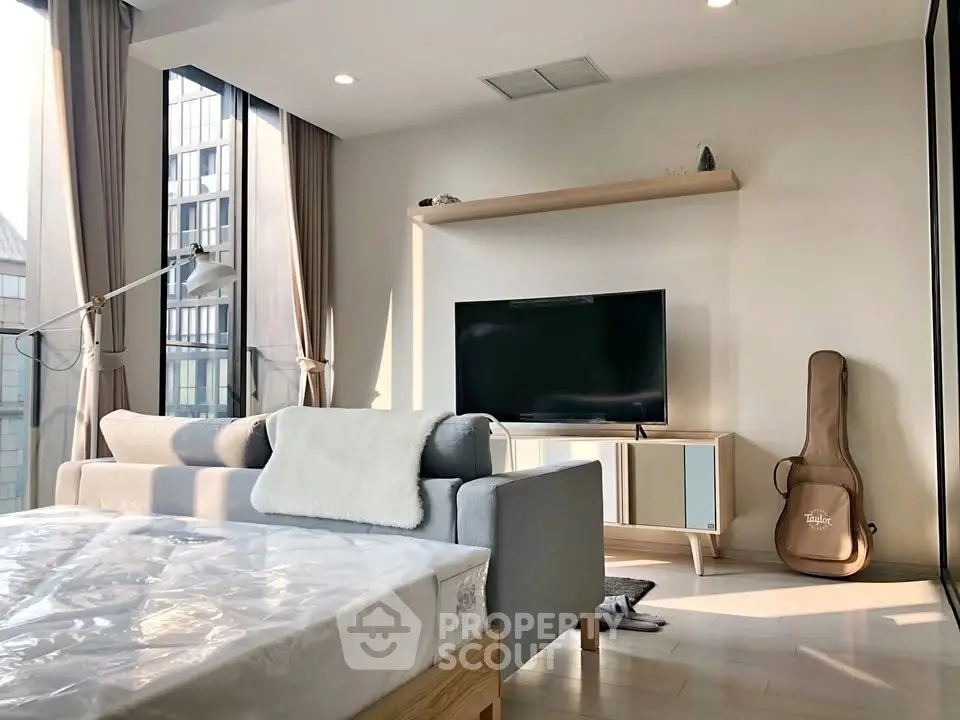 Modern living room with large windows, stylish furniture, and natural light in a high-rise apartment.