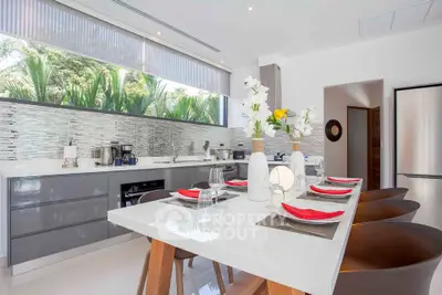Modern kitchen with sleek design, open layout, and stylish dining area, featuring stainless steel appliances and large windows.