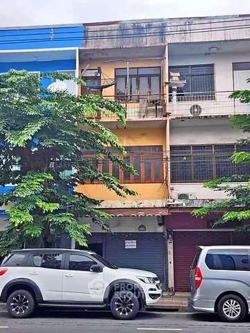 Charming urban building facade with potential for renovation, featuring a balcony and street view.