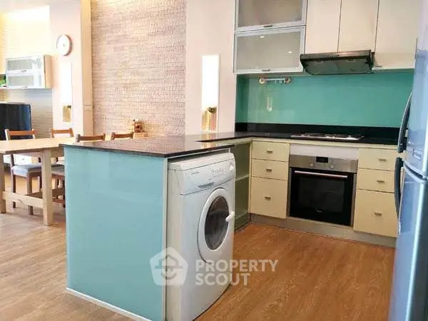 Modern kitchen with washing machine and dining area, featuring sleek design and open layout.